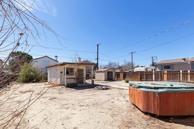 view of yard with an outdoor structure, fence, a shed, and a hot tub