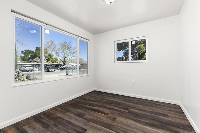 spare room with baseboards and dark wood finished floors