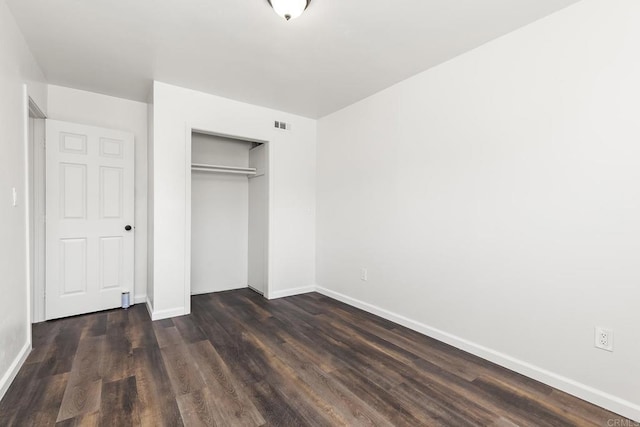 unfurnished bedroom with a closet, baseboards, visible vents, and dark wood-style flooring