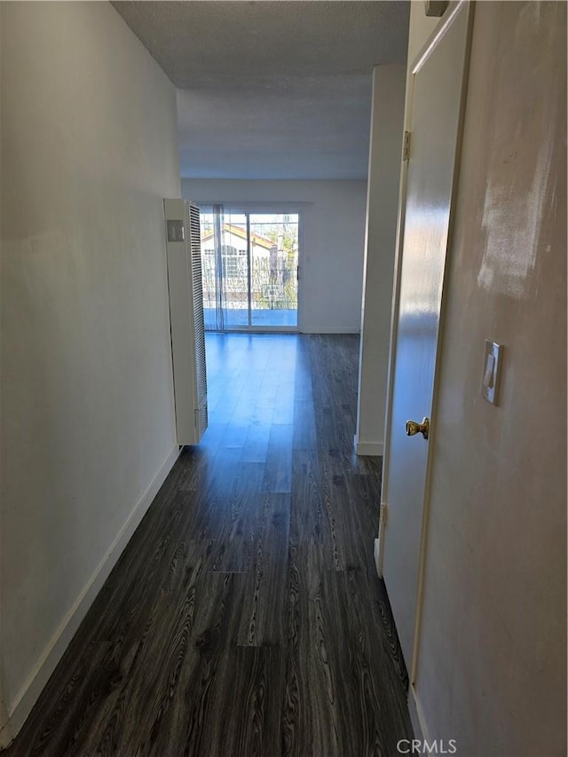 hall featuring baseboards and dark wood finished floors