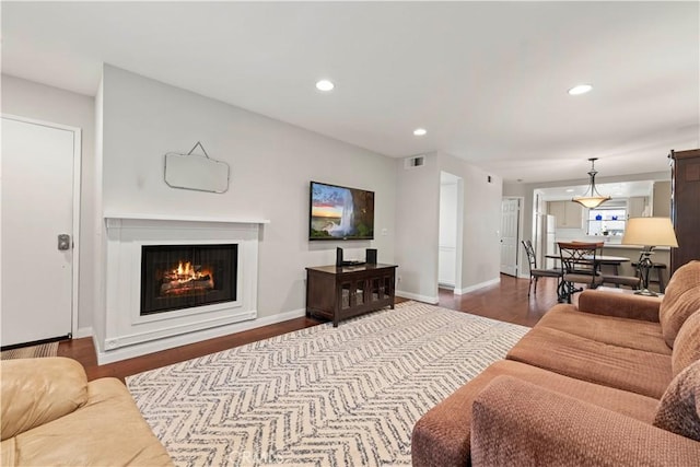 living area featuring recessed lighting, dark wood-style floors, visible vents, and a lit fireplace