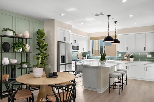 1810 E 1st St Unit 130, Santa Ana, CA 92705 - kitchen featuring appliances with stainless steel finishes, a kitchen island, tasteful backsplash, white cabinets, and recessed lighting