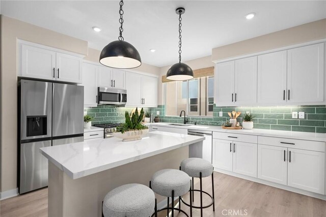 1810 E 1st St Unit 130, Santa Ana, CA 92705 - kitchen with appliances with stainless steel finishes, a sink, white cabinetry, a kitchen island, and light wood finished floors