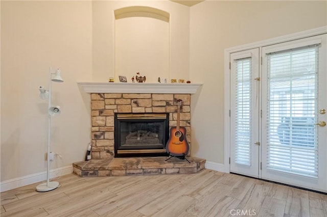 living room with a fireplace, baseboards, and wood finished floors