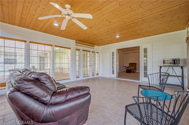 sunroom / solarium featuring wood ceiling, a ceiling fan, and a healthy amount of sunlight