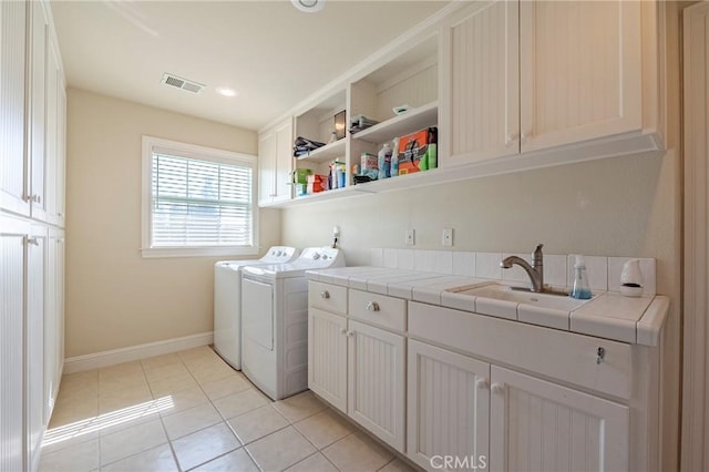 washroom featuring light tile patterned floors, visible vents, cabinet space, a sink, and washer and dryer