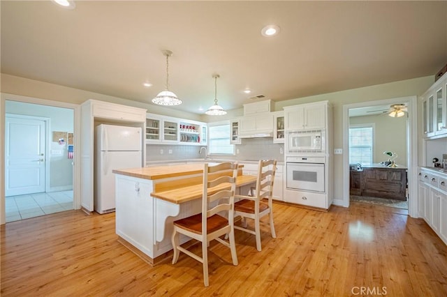 kitchen featuring light wood finished floors, white appliances, white cabinetry, and a sink