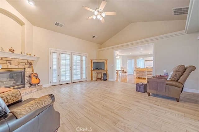 living area featuring light wood-type flooring, visible vents, ceiling fan, and a fireplace