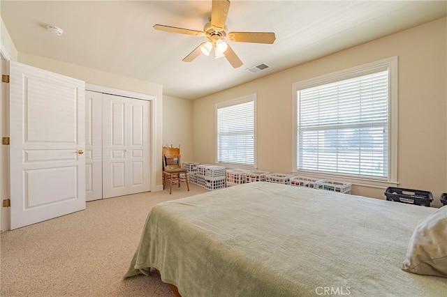 carpeted bedroom with multiple windows, a ceiling fan, visible vents, and a closet