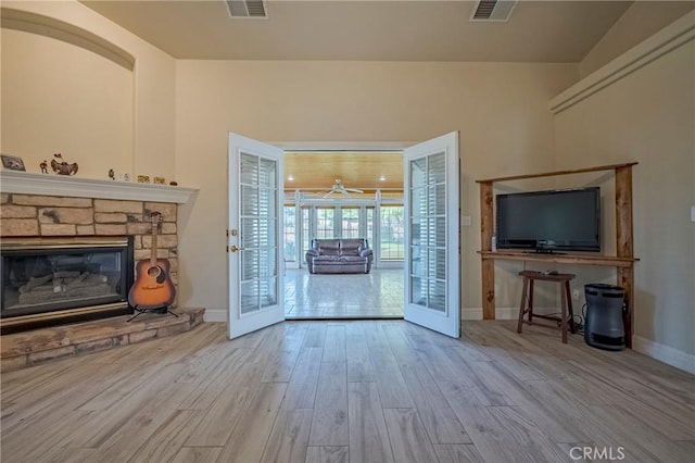 unfurnished living room with visible vents, french doors, baseboards, and wood finished floors