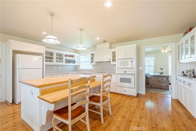 kitchen featuring white appliances, decorative backsplash, glass insert cabinets, light wood-style floors, and white cabinetry