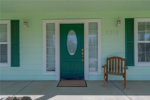 view of exterior entry featuring concrete block siding and covered porch