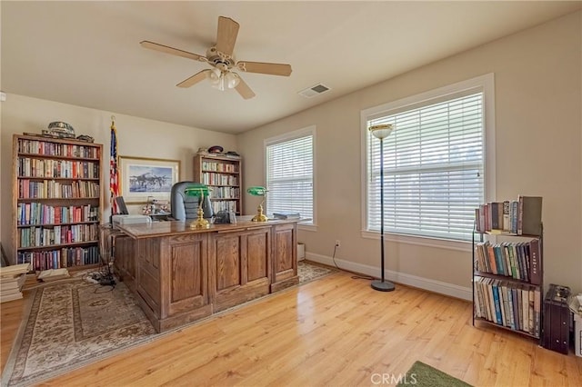 office space featuring a healthy amount of sunlight, light wood-style floors, visible vents, and ceiling fan