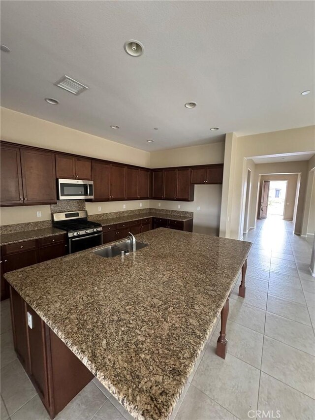 1572 Humboldt Peak, Beaumont, CA 92223 - kitchen with appliances with stainless steel finishes, a sink, dark stone counters, a spacious island, and light tile patterned flooring