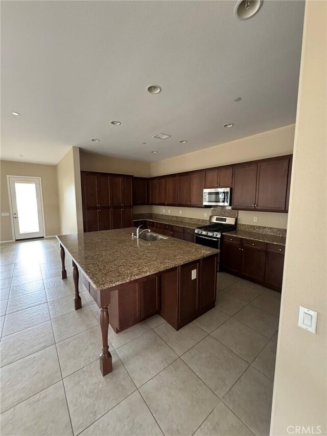 1572 Humboldt Peak, Beaumont, CA 92223 - kitchen featuring appliances with stainless steel finishes, a sink, a center island with sink, dark stone countertops, and light tile patterned flooring
