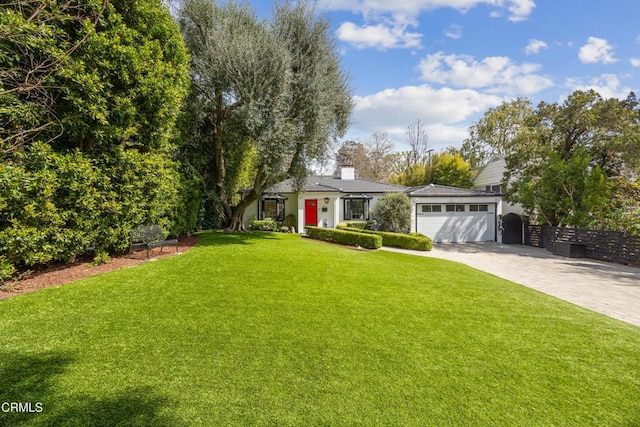 view of front of property featuring driveway, a front lawn, fence, an attached garage, and a chimney