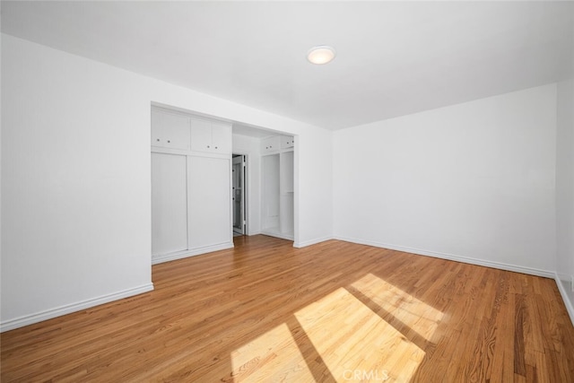unfurnished bedroom with baseboards, light wood finished floors, and a closet