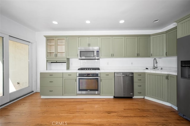 kitchen featuring tile counters, green cabinets, and stainless steel appliances