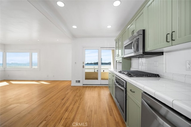 kitchen featuring tile counters, appliances with stainless steel finishes, a wealth of natural light, and light wood-type flooring