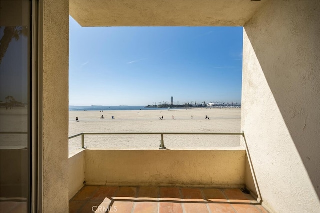 balcony with a water view and a view of the beach