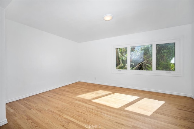 spare room featuring baseboards and light wood finished floors