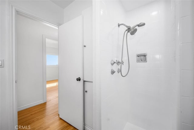 full bathroom with tiled shower and wood finished floors