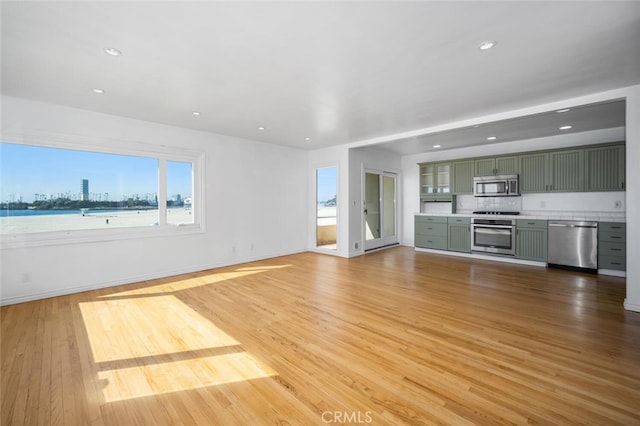unfurnished living room featuring a healthy amount of sunlight, baseboards, recessed lighting, and light wood finished floors