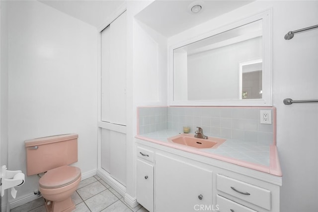 bathroom with decorative backsplash, tile patterned floors, baseboards, vanity, and toilet
