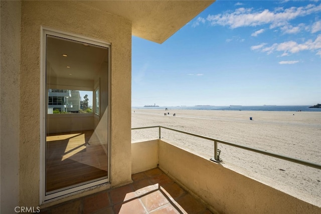 balcony with a water view and a view of the beach