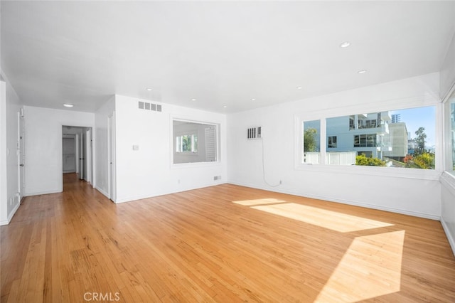 unfurnished living room featuring visible vents, a healthy amount of sunlight, and light wood-style floors