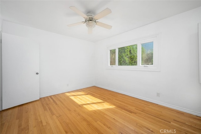 spare room featuring baseboards, ceiling fan, and wood finished floors