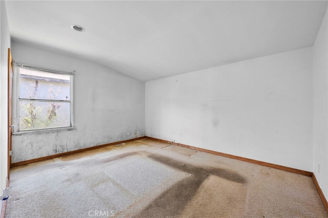 carpeted empty room with baseboards and vaulted ceiling