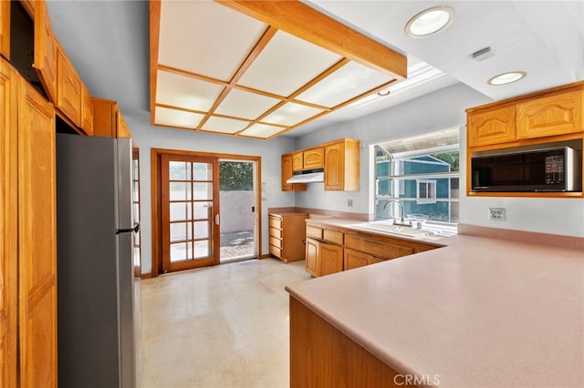 kitchen featuring a sink, under cabinet range hood, freestanding refrigerator, light wood-style floors, and black microwave