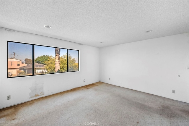 carpeted empty room with a textured ceiling