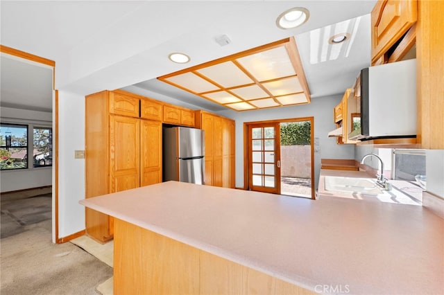 kitchen with a wealth of natural light, a peninsula, freestanding refrigerator, and a sink