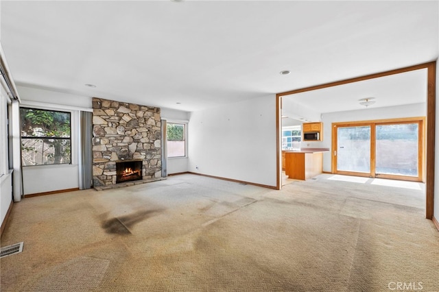 unfurnished living room with visible vents, baseboards, light colored carpet, and a fireplace