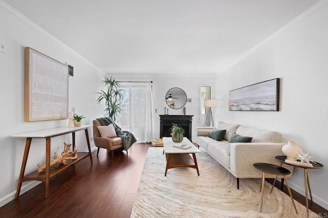 living room featuring a fireplace with raised hearth, wood finished floors, baseboards, and ornamental molding