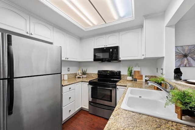 kitchen with dark wood-style floors, a sink, light countertops, appliances with stainless steel finishes, and white cabinetry