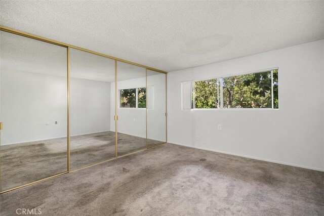 2405 Via Mariposa W Unit 2G, Laguna Woods, CA 92637 - unfurnished bedroom featuring carpet floors, a textured ceiling, and a closet