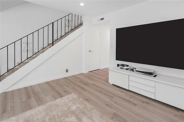 unfurnished living room featuring light wood finished floors, visible vents, baseboards, stairs, and recessed lighting