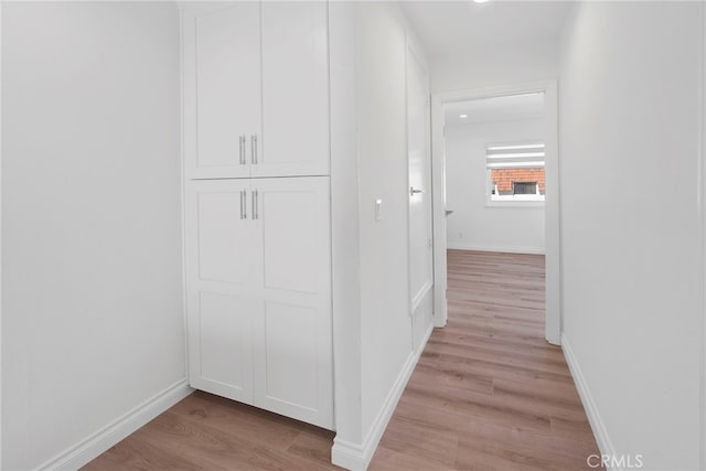 hall featuring light wood-style flooring and baseboards