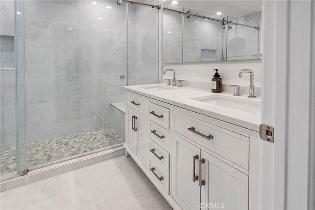 bathroom featuring double vanity, a stall shower, and a sink