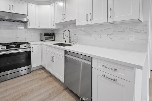 kitchen with under cabinet range hood, a sink, stainless steel appliances, light wood finished floors, and light countertops