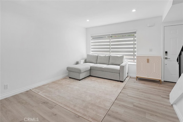 unfurnished living room with recessed lighting, baseboards, and light wood finished floors