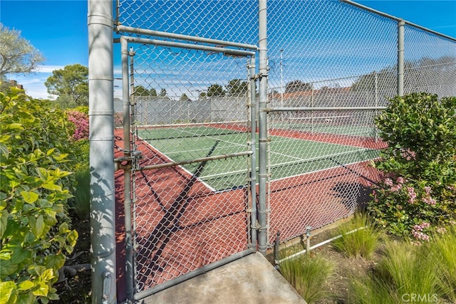 view of tennis court featuring a gate and fence