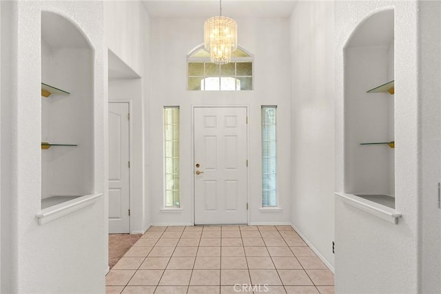 foyer entrance featuring a notable chandelier, light tile patterned flooring, baseboards, and a healthy amount of sunlight