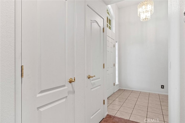 foyer entrance featuring a chandelier, baseboards, and light tile patterned flooring