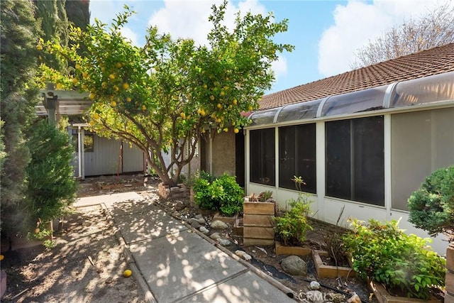 back of property with a sunroom, a tiled roof, and stucco siding