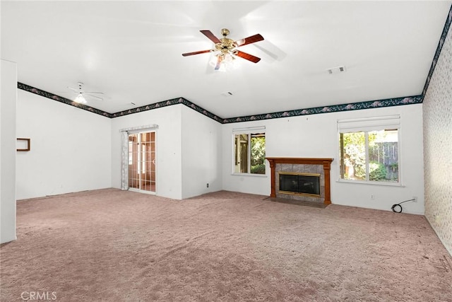 unfurnished living room with carpet flooring, a fireplace with flush hearth, visible vents, and ceiling fan