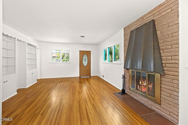 foyer featuring visible vents, baseboards, wood finished floors, and a fireplace